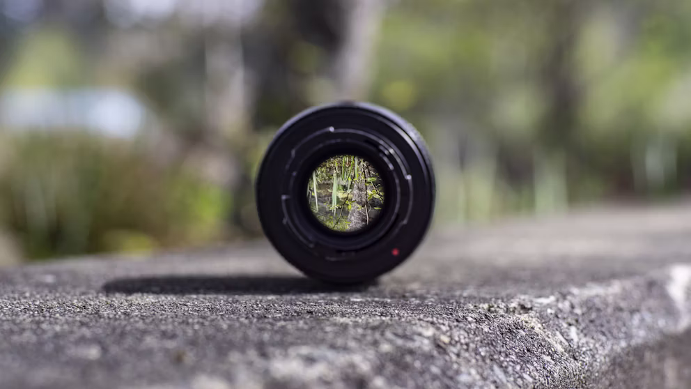 Black DSLR camera lens resting on a concrete surface, symbolizing focus
